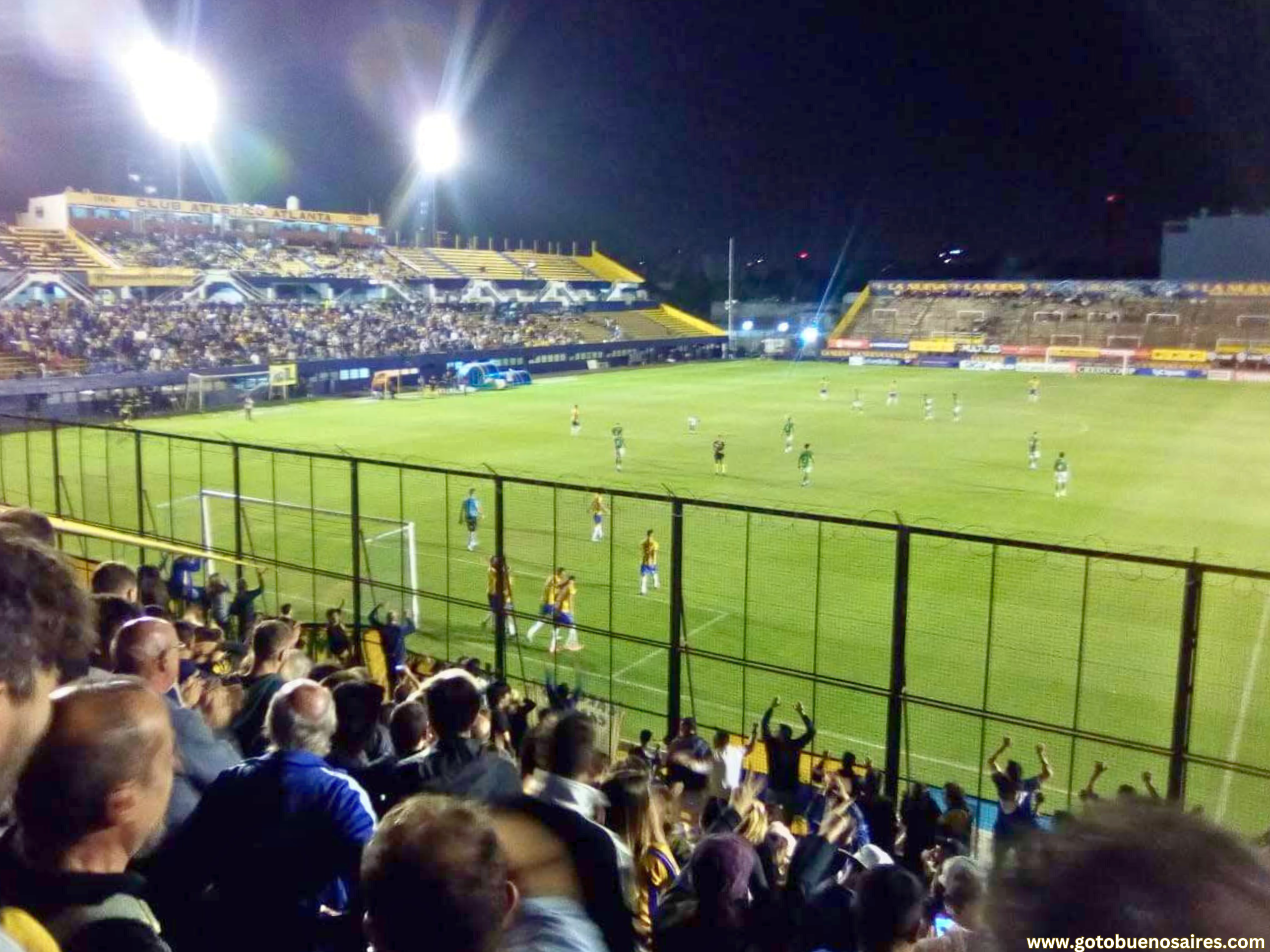 A vibrant football game at the Atlanta Football Club in Villa Crespo, Buenos Aires, with players in action on the field and a cheering crowd in the stands.