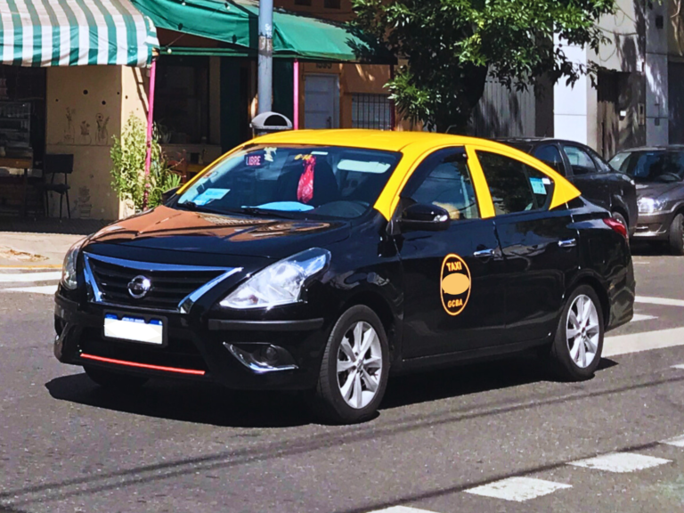 A yellow and black taxi driving on a street in Buenos Aires, Argentina.