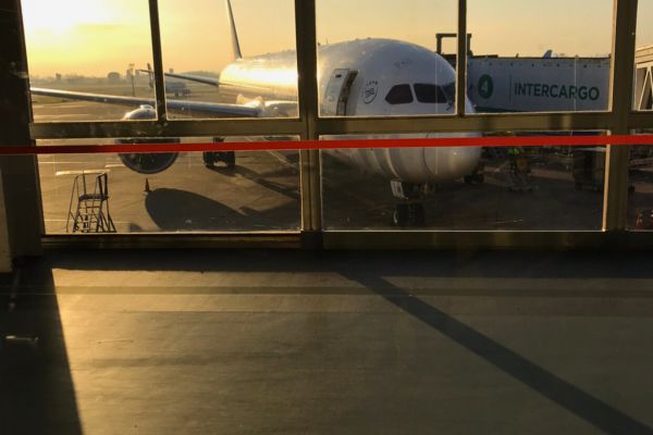 Airplane parked at a gate at Ezeiza Airport in the early morning sunshine, viewed through a window.