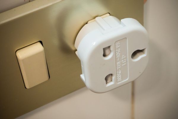 Image of a travel adaptor connected to a plug socket.