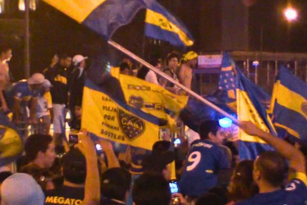 Boca Juniors fans waving flags and celebrating at El Obelisco in Buenos Aires.