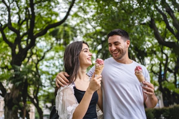 A couple enjoying ice cream while strolling through the streets of Buenos Aires, Argentina, on a sunny day.