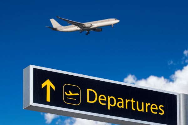 Plane taking off into the sky with a departures sign in the foreground.