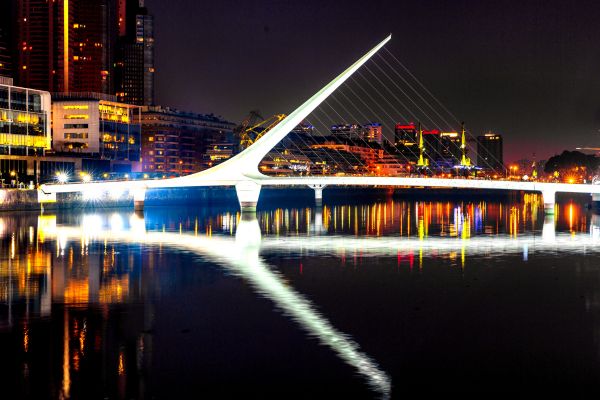 Puente de la Mujer Bridge lite up at night in Buenos Aires.