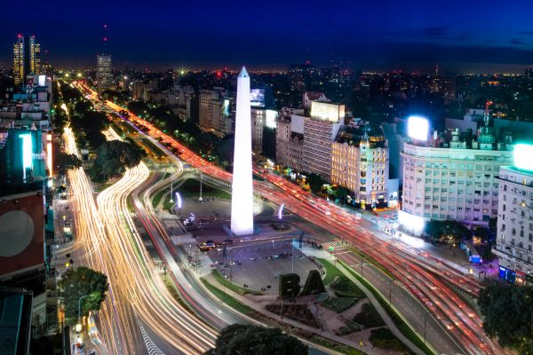 Aerial view of the Obelisco in Buenos Aires, Argentina, illuminated at night with surrounding city lights.