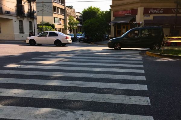 A pedestrian zebra crossing on a busy street in Buenos Aires, with vehicles in the background.